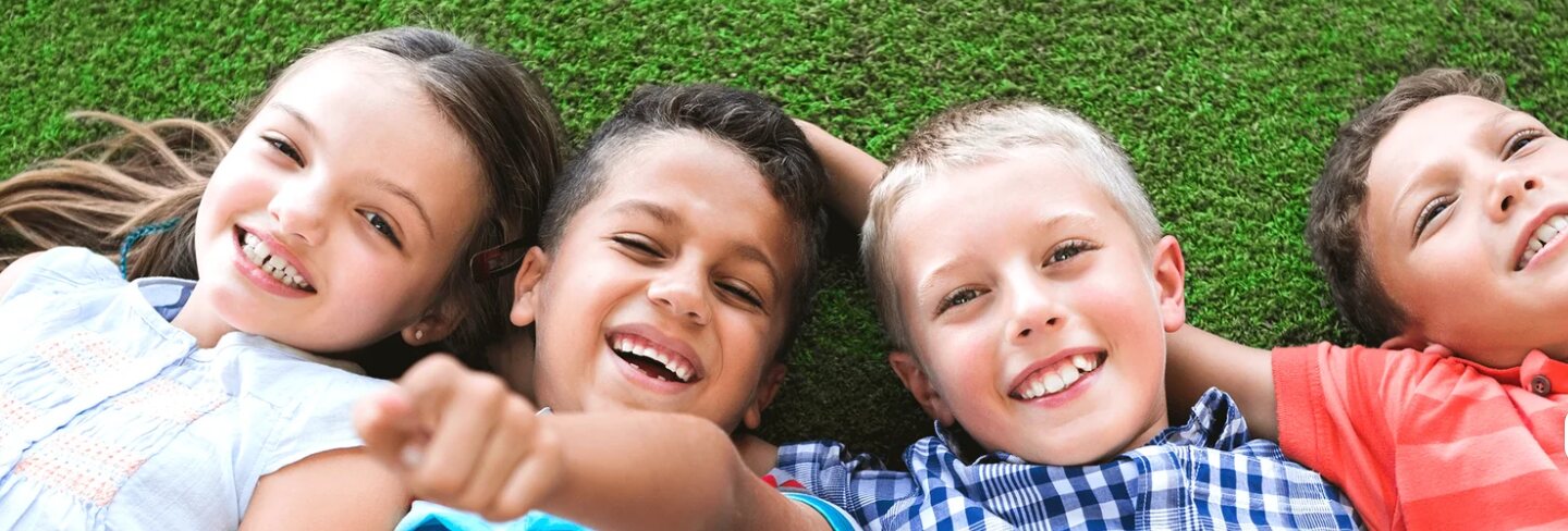 Kids lying on the grass laughing together